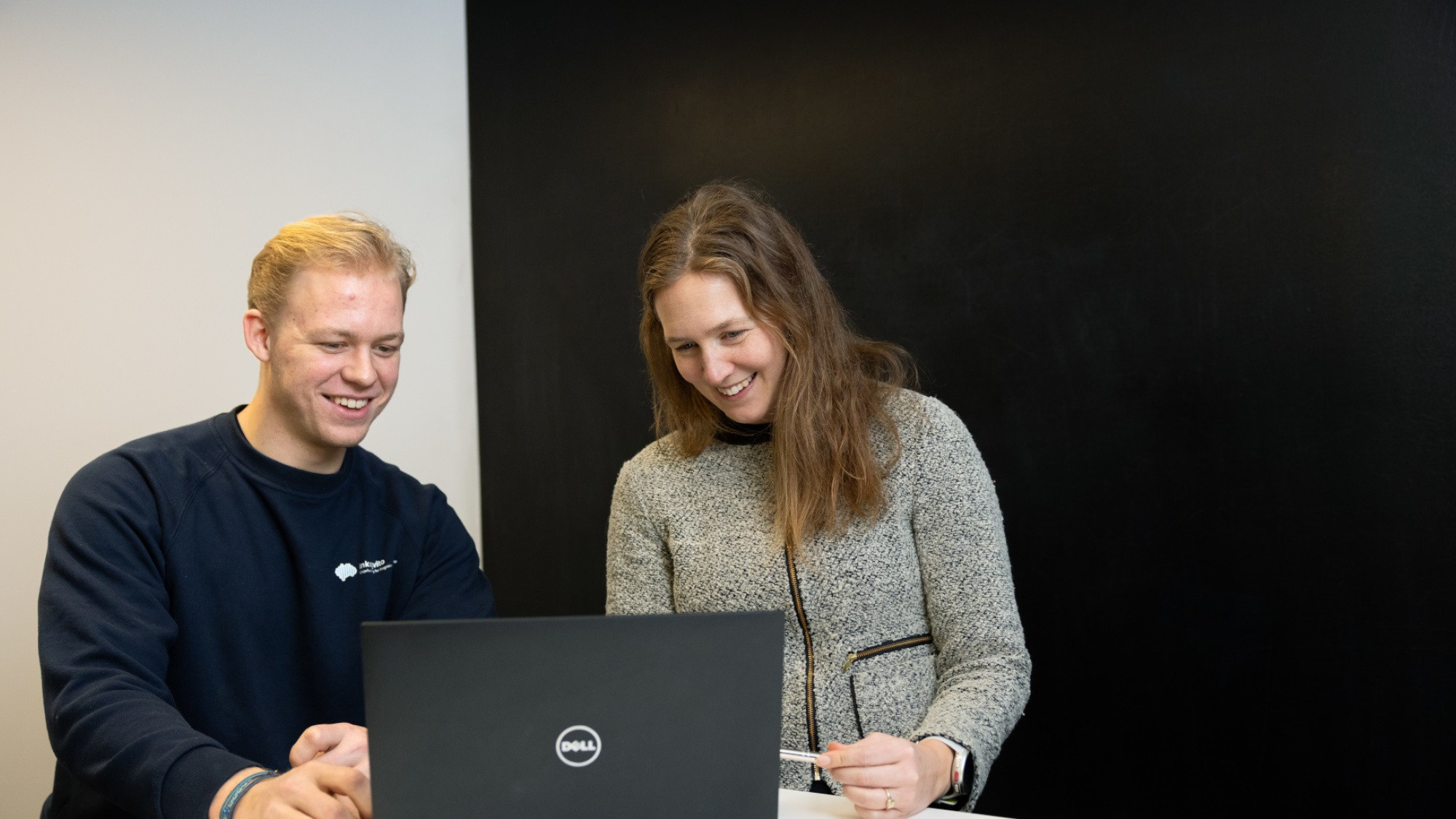 En mann og en kvinne sitter foran laptopen og smiler.